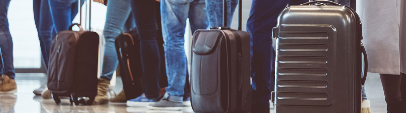 Row of people with suitcases.