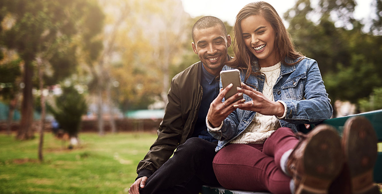 Young couple looking at phone in park.