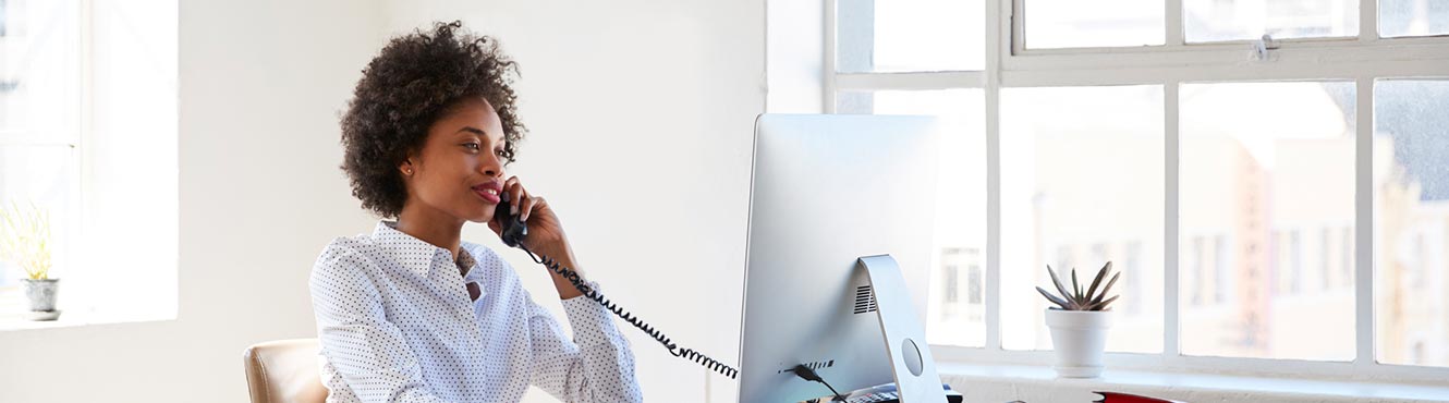 Woman at computer and on phone.